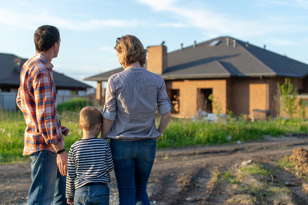Couple and child standing and looking at new house.