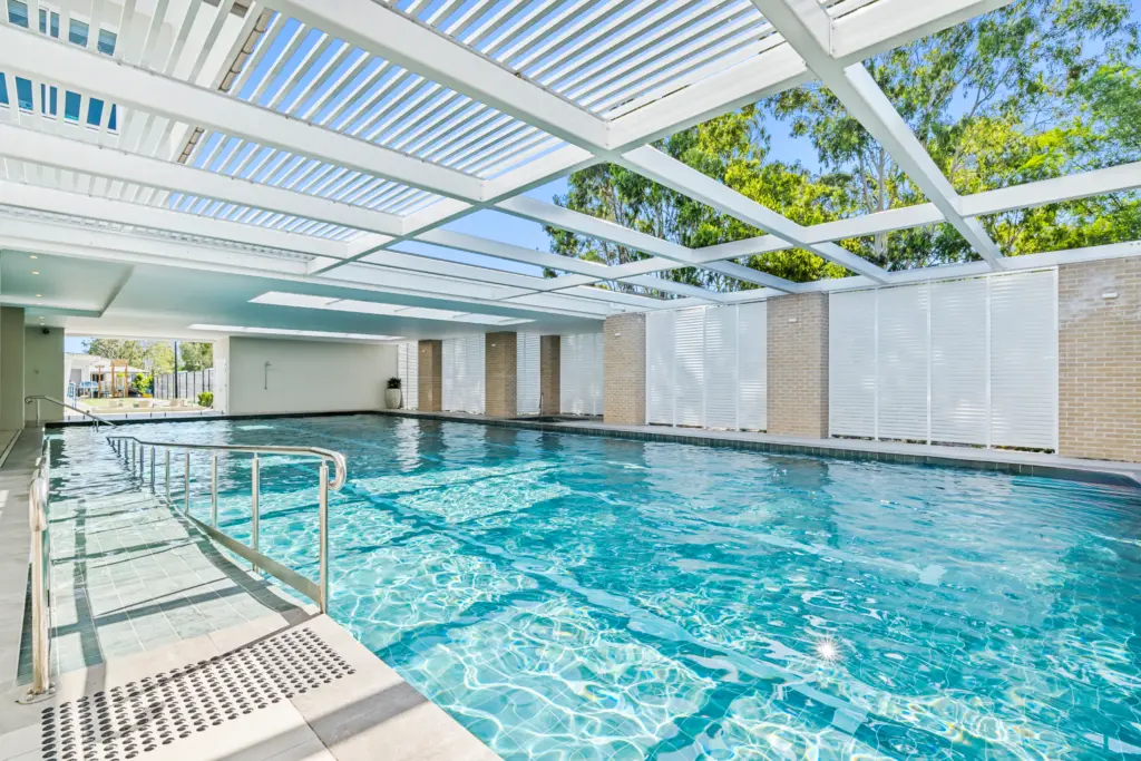 Modern covered swimming pool with white pergola roof