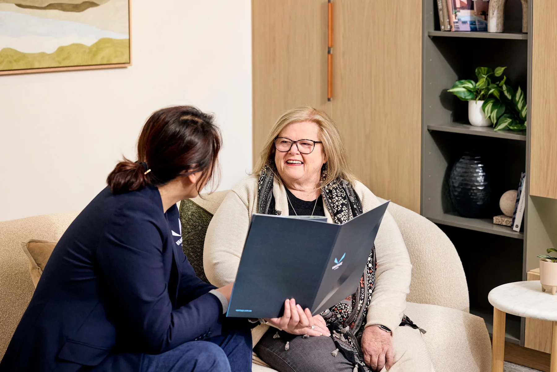 Two women reviewing documents on a sofa
