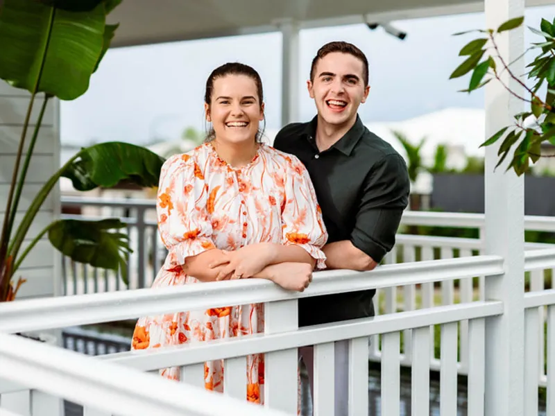 Smiling couple on white verandah with tropical plants