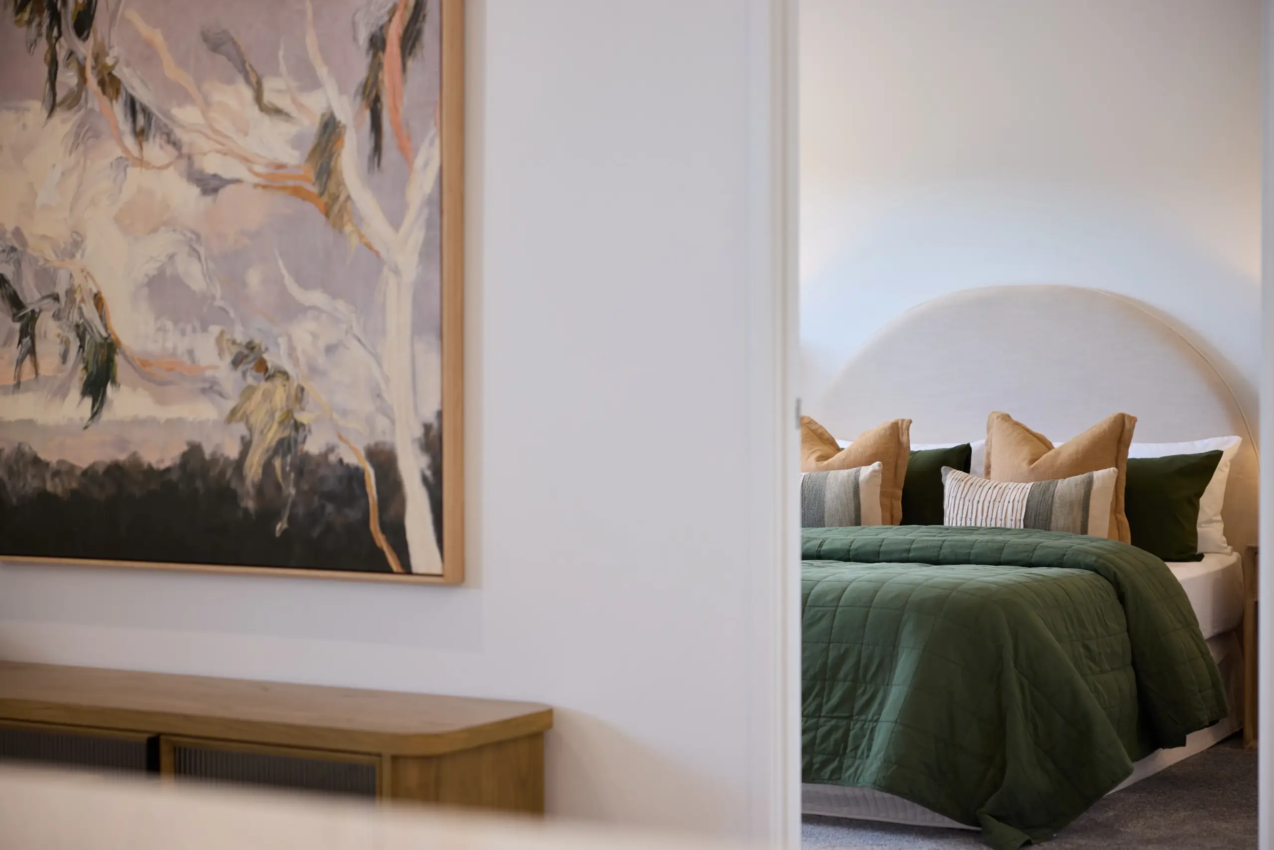 Modern bedroom with green quilt and abstract artwork