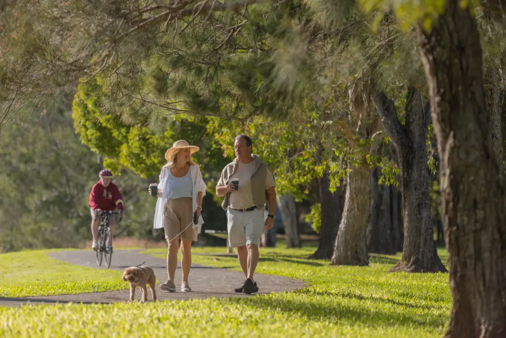 Couple walking dog in sunny park