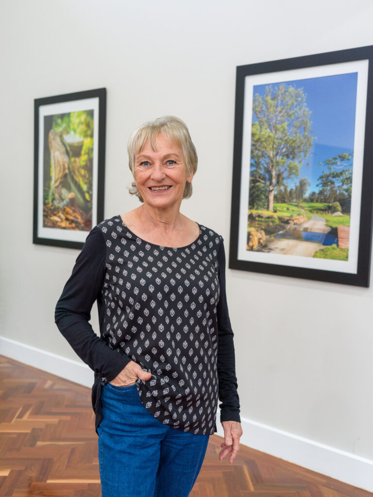 Vantage Logan Village Links resident Shirley Le Marquand in the Clubhouse in front of framed resident photography