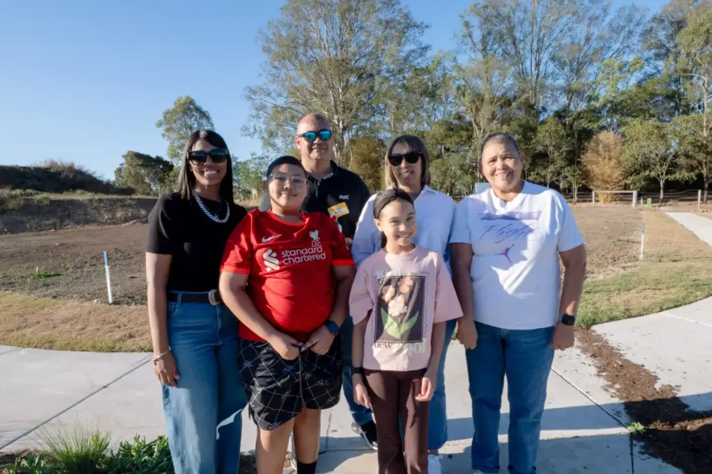 Six people smiling together in a sunny park